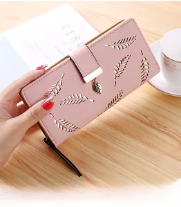 Detail of soft pink PU leather wallet with laser-cut leaf pattern and golden pendant
