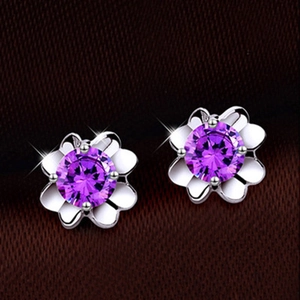 Close-up of silver flower stud earrings featuring a purple zircon stone in the center
