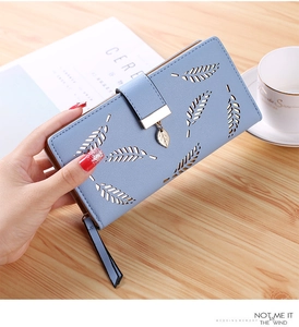 Close-up of light blue long wallet featuring leaf cut-outs and a gold leaf pendant