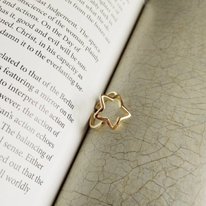 Dettaglio dell'anello a stella d'oro su pagine di libro vintage con sfondo materico