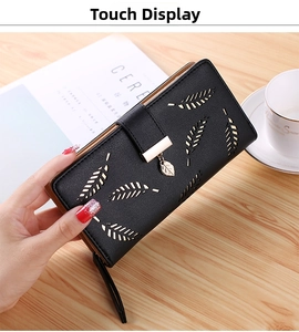 Close-up of black long leather wallet featuring leaf cutouts and golden pendant detail