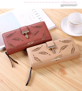 Close-up of hollow leaf patterns and metal pendants on long faux leather wallets