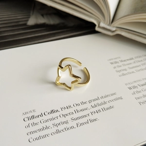 Primo piano artistico di un anello dorato a forma di stella su un libro di moda vintage