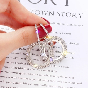 Close-up of hand holding silver sparkling hoop earrings with pavé rhinestones