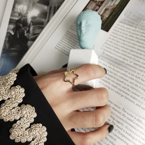 Dettaglio di un anello a stella dorato vintage su una modella con sfondo artistico