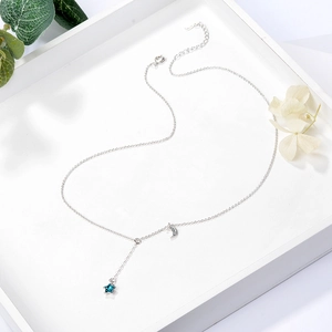 Blue star and moon pendant necklace for women with elegant silver chain on a white tray
