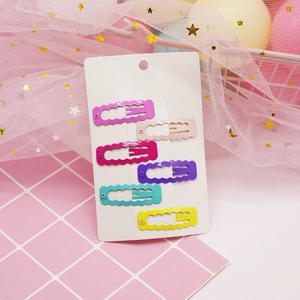 Close-up of six colorful wavy snap clips on display card with glossy lacquered finish