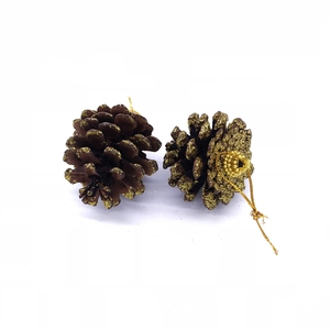 Close-up of two natural pine cones with golden glitter edges and hanging strings