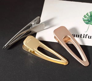 Detailed view of three minimalist metal hair clips in silver, gold, and rose gold finishes
