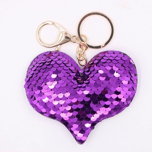 Sparkling purple sequin heart keychain with golden metal clasp on white background