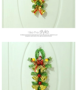 Detail of Christmas wall hanging with green pine needles, gold bells and Santa figurine