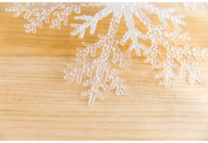 Détail macro d'un flocon de neige en acrylique sur fond de bois clair pour Noël