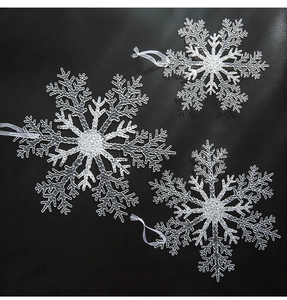 Détail de trois flocons de neige en acrylique blanc pailleté avec rubans de suspension