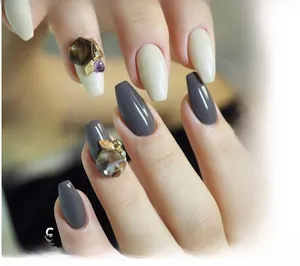 Macro shot of long trapezoid nails with amber resin stones and gold leaf accents