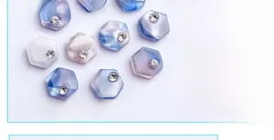 Detailed view of hexagonal nail art charms with blue marble pattern and a tiny center rhinestone