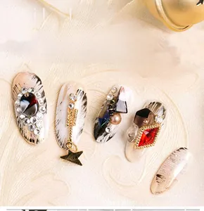 Close-up of marble texture nail art with rhinestones, pearls, and gold star charms