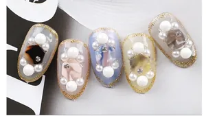 Macro detail of luxury press-on nails with large pearls, gold glitter edges and matte finish