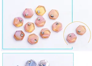 Macro detail of hexagonal resin nail charms with gradient colors and inlaid rhinestones