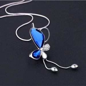 Detailed macro view of a silver butterfly pendant with blue crystals and tassels