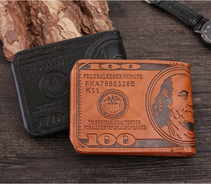 Close-up of vintage bifold wallets with $100 bill pattern on dark wood texture