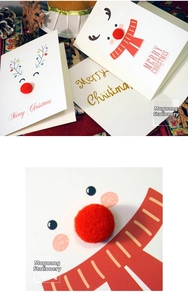 Detail of Christmas greeting card featuring a 3D red pom-pom nose on a reindeer design