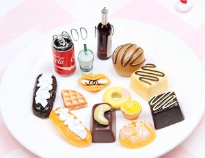 Miniature resin food charms featuring cola, donuts and cakes on a white ceramic plate
