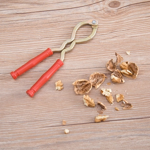 Durable iron nutcracker with ergonomic red handles on a rustic wooden surface