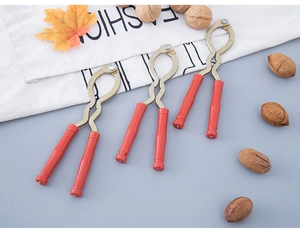 Three metal nutcrackers with red handles displayed with walnuts and autumn leaves