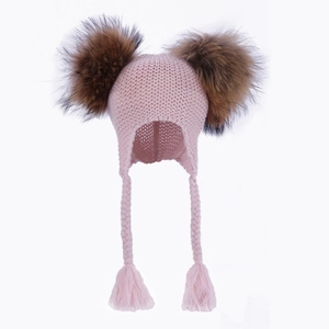 Close-up of pink knit kids earflap hat with dual fluffy brown faux fur pom poms and braids