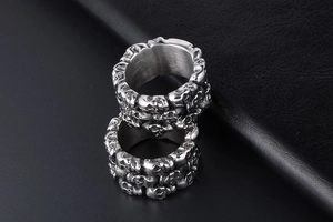 Detailed close-up of stacked silver titanium steel rings with embossed skull patterns