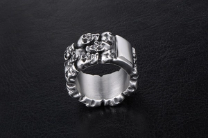 Close-up of silver titanium steel ring with 3D skull embossments on leather background