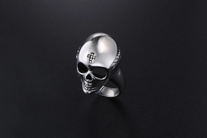Macro shot of polished gothic skull ring with cross detail and punk metal textures