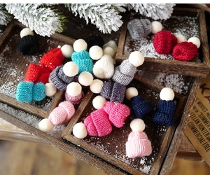 Close-up of mini knitted Christmas hats in various colors with white pom-poms on wood