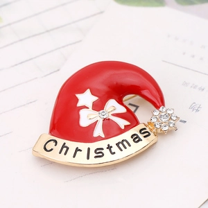 Detailed view of a red enamel Christmas hat brooch with gold metal and rhinestones