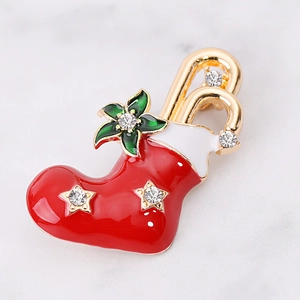 Detail of a Christmas stocking brooch with red enamel, white trim, and a green leaf charm