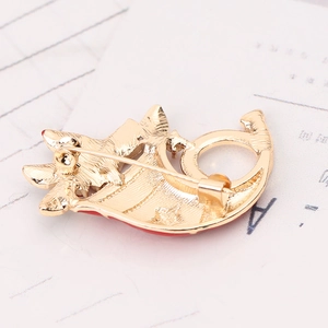 Detailed view of the golden metal brooch back with pin clasp and red enamel accents