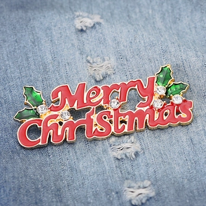 Detailed view of Merry Christmas brooch with red enamel and rhinestones on denim