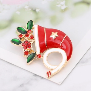 Macro shot of colorful enamel Christmas brooch with red rhinestones on white card