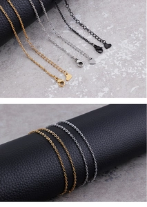 Detail of gold, silver, and black stainless steel O-chains with lobster clasps and heart charms