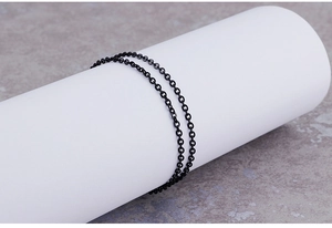 Detail of matte black stainless steel O-link chain wrapped on a white cylinder stand