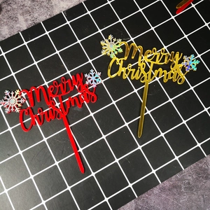 Close-up of red and gold acrylic Merry Christmas cake toppers with shiny snowflake details