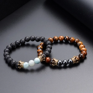 Detailed shot of crown charms on lava stone and tiger eye beaded bracelets
