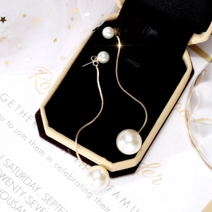 Elegant long pearl tassel earrings in gold finish displayed on black velvet jewelry box