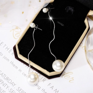 Close-up of elegant long pearl tassel earrings on a velvet jewelry box with starry mesh