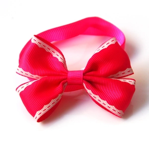 Close-up of a red ribbed ribbon pet bow tie with white scalloped edges and gold bell