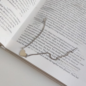 Detailed view of S925 sterling silver heart pendant necklace on an open book