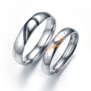 Close-up of heart-shaped titanium steel couple rings with Real Love engraving detail.