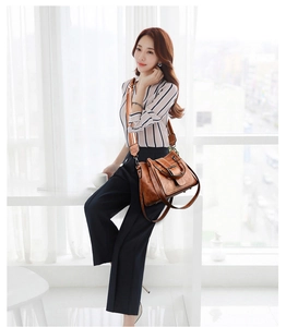 Detail of a brown lychee pattern leather bucket bag with striped fabric shoulder strap
