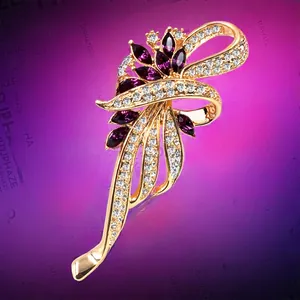 Macro view of gold-plated ribbon brooch featuring purple marquise gems and white crystals