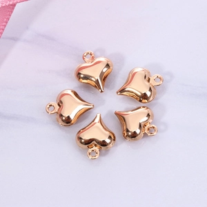 Set of five gold heart-shaped pendant charms for DIY jewelry on marble background